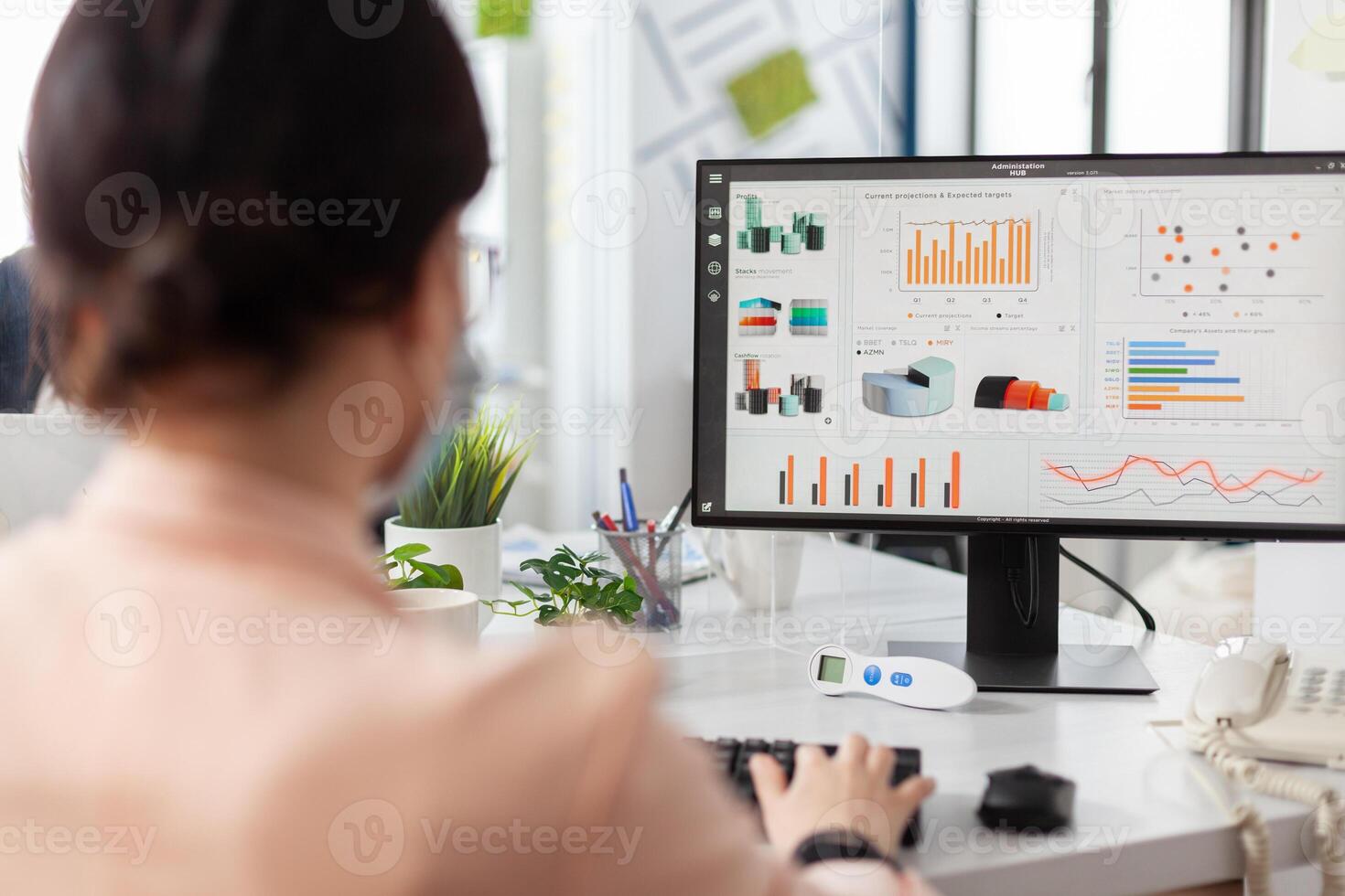 Businesswoman working at financial presentation analyzing company graphs in startup office during global pandemic. Executive manager wearing medical face mask to prevent infection with covid19 photo