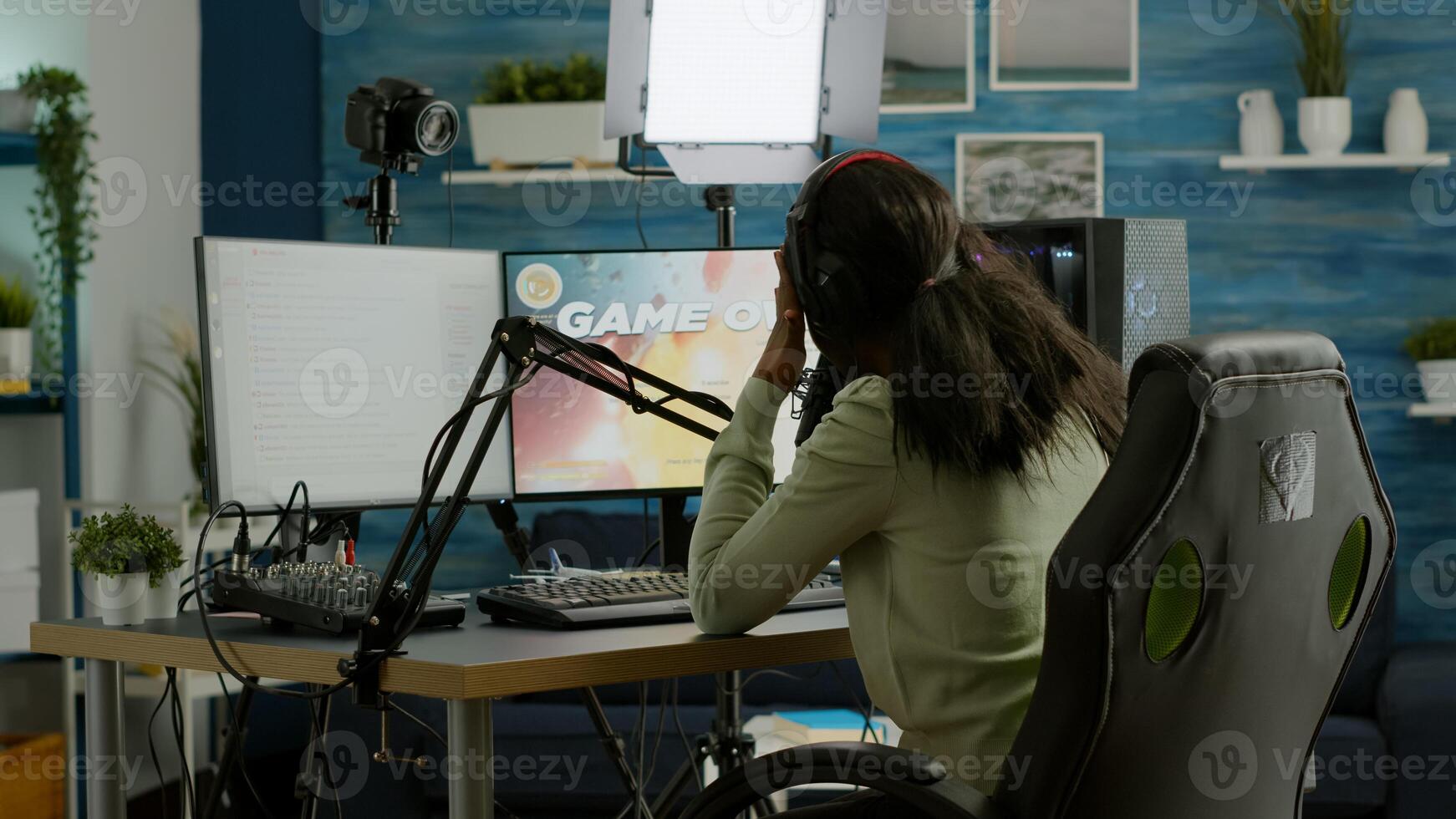 African streamer regrets losing live space shooter game tournament touching temple, chatting with team. Professional gamer streaming online games with new graphics on powerful computer. photo