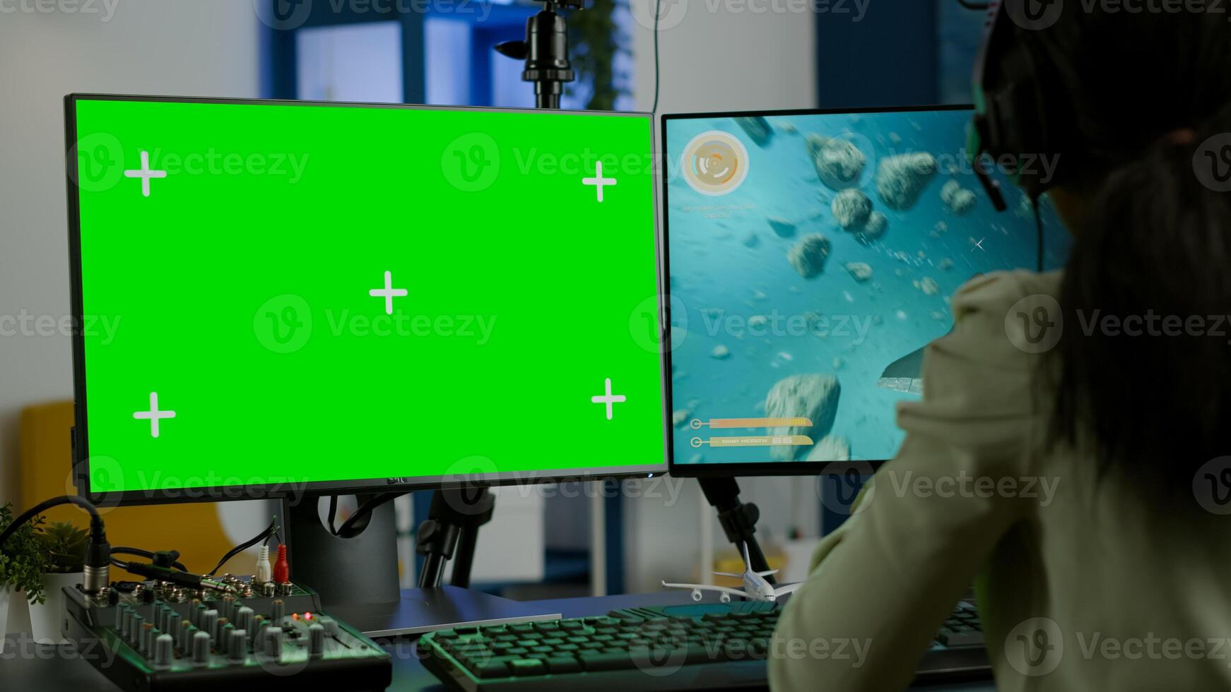 Black woman gamer streaming online videogame on powerful computer with green screen mock up chroma key display. Cyber player using professional pc with isolated desktop playing shooter game in headset photo