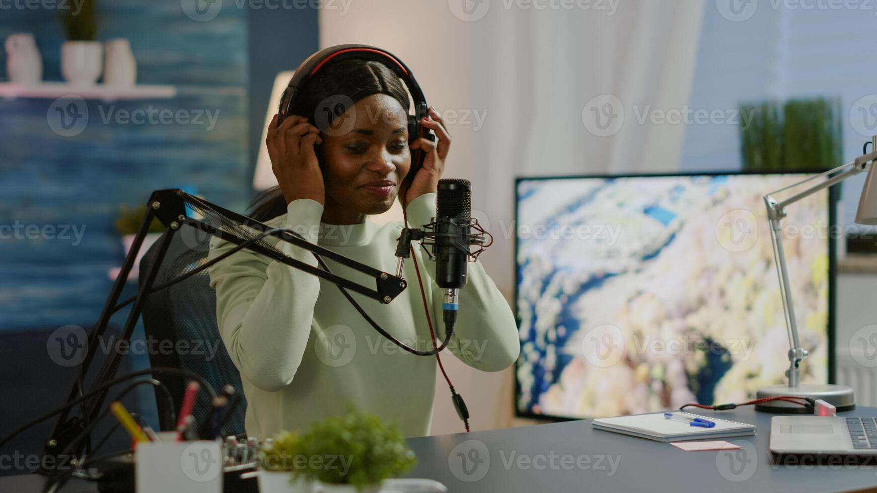African blogger smiling at audience while filming podcast, looking at camera putting on headset. On-air production internet broadcast host streaming live content, recording digital social media photo