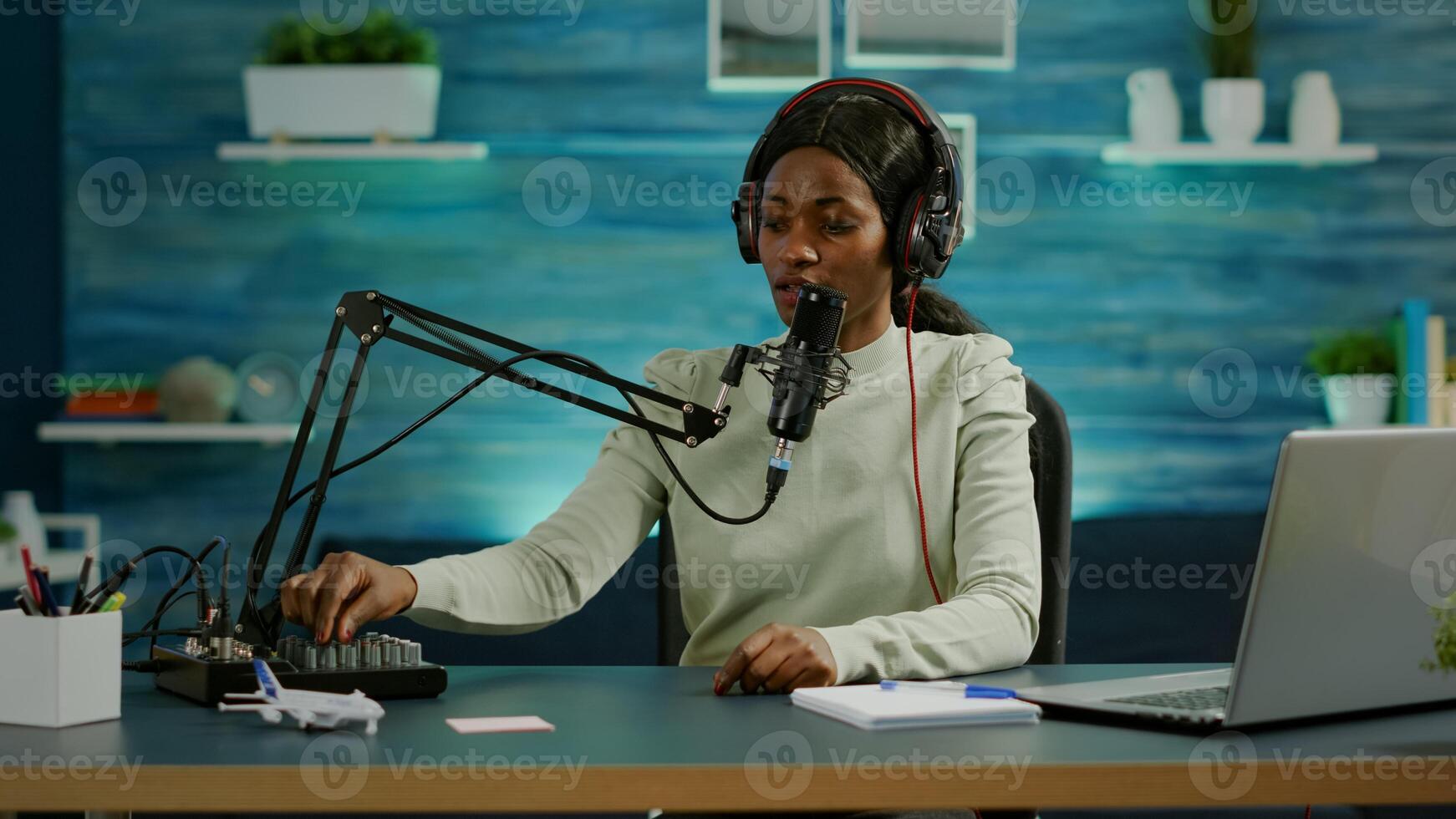 Black blogger woman recording for her blog in home studio reading messages checking sound on mixer. On-air online production internet broadcast show host streaming live content for social media photo