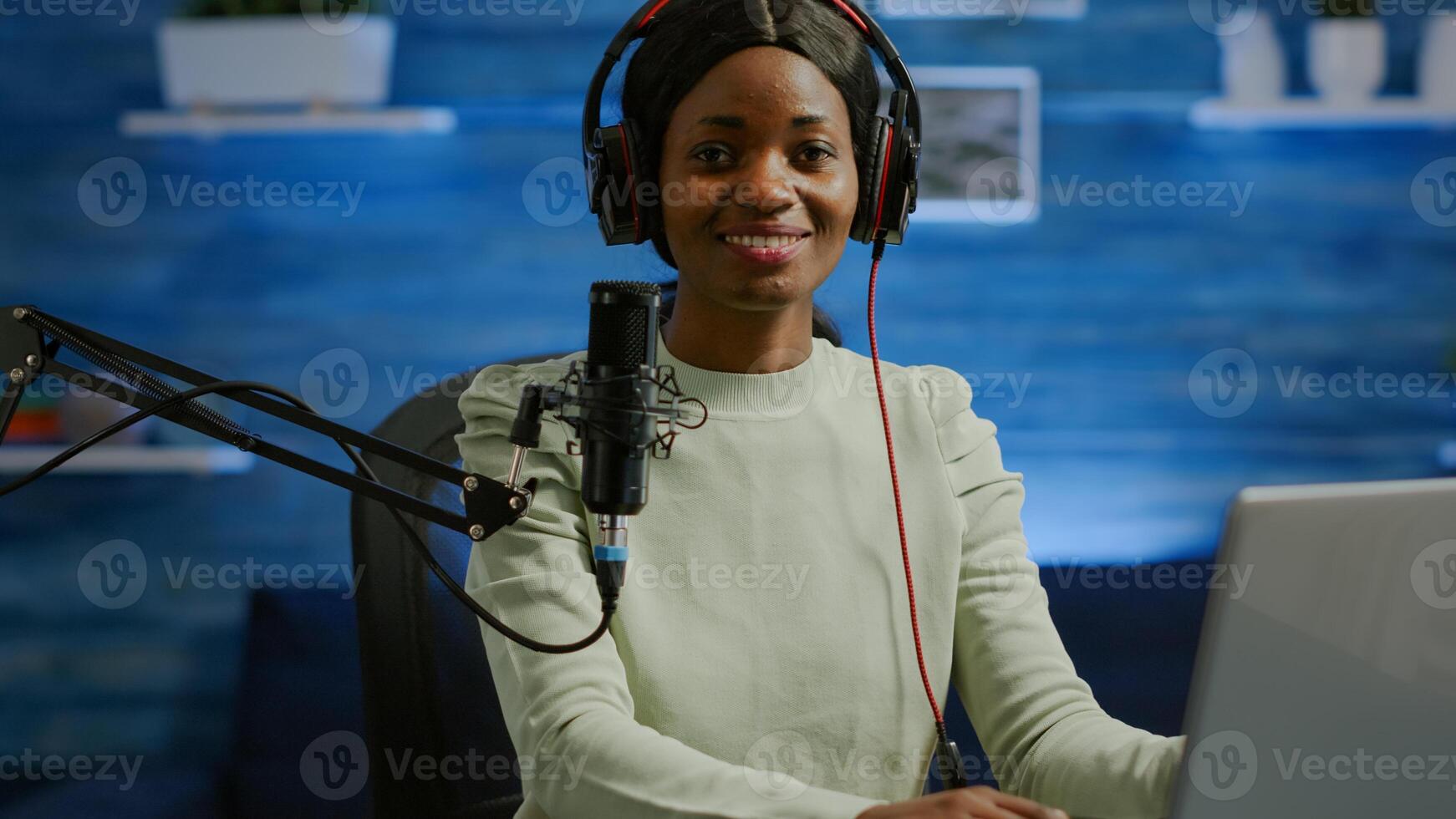Portrait of african smiling blogger looking at camera before starting live from home studio podcast. Content creator vlogger woman recording brodcast streaming online content for social media photo