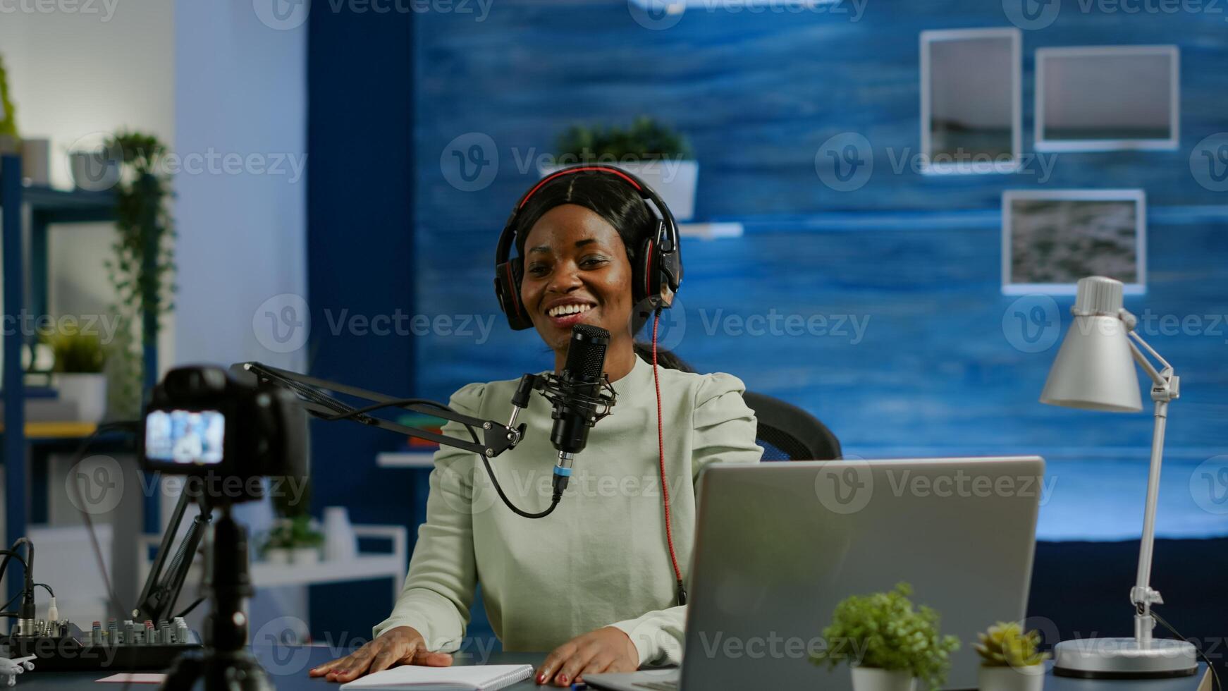 Woman african vlogger recording to camera tutorial about lifestyle in home podcast studio during livestreaming. On-air online production internet broadcast show host streaming live content for social media photo