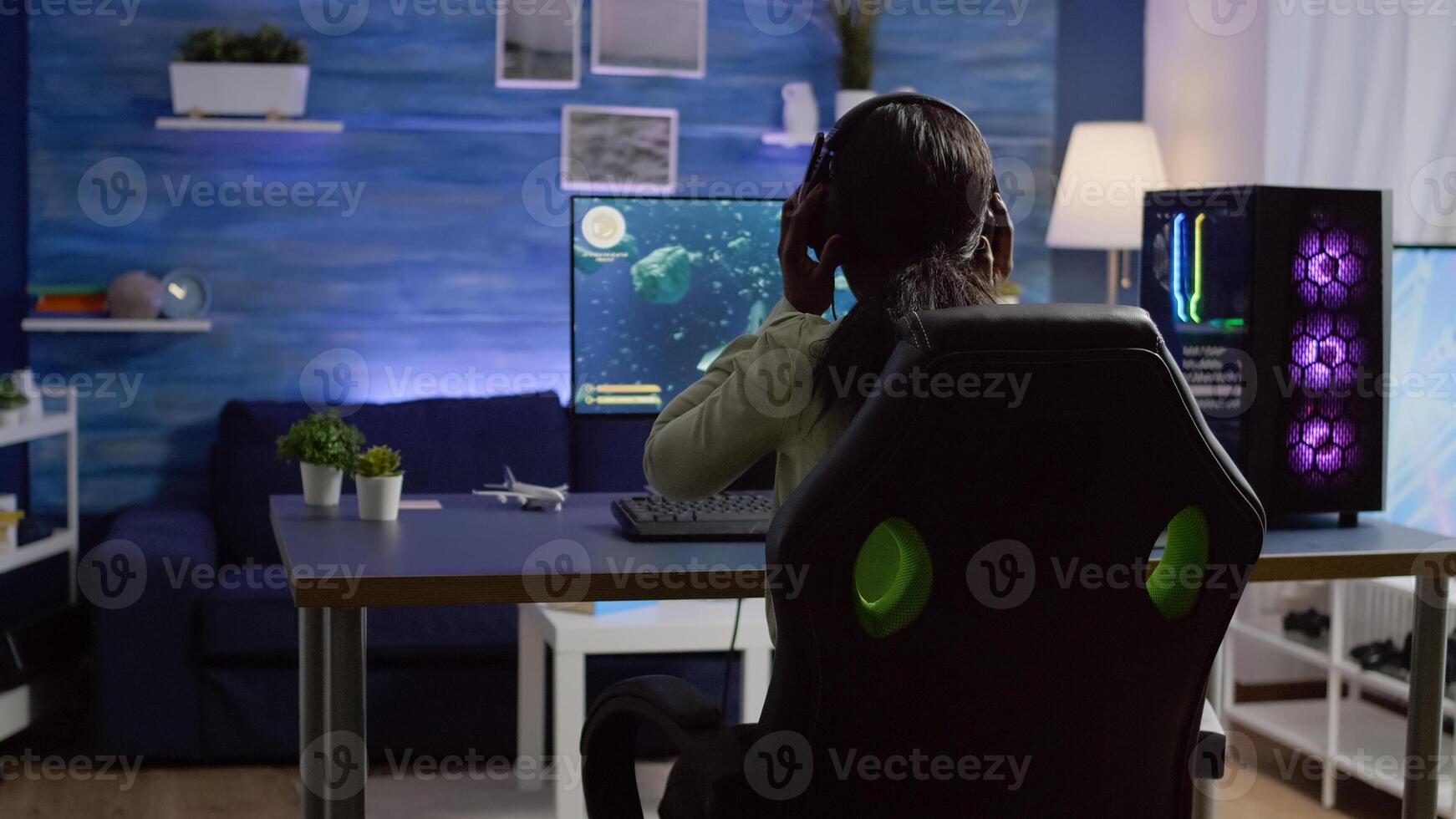 Pro gamer playing shooter game at gaming home studio using RGB mouse keyboard on powerful computer. Virtual online streaming setup with neon lights cyber performing during game tournament photo