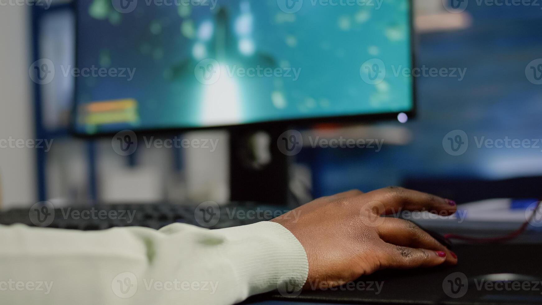 Close up of african woman cyber moving professional mouse with RGB playing space shooter game. Player using powerful gaming computer in home studio of esport videogame typing at keypad photo