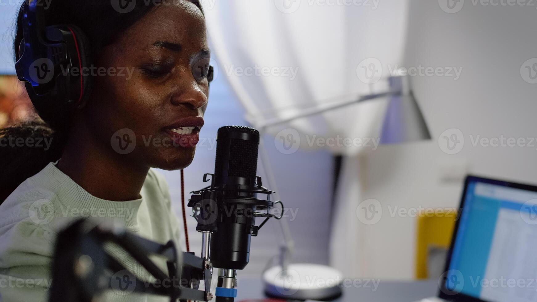 Close up of african blogger woman speaking at microphone during podcast using professional recording technology in home studio. Content creator making serires for channel, streaming online broadcast photo