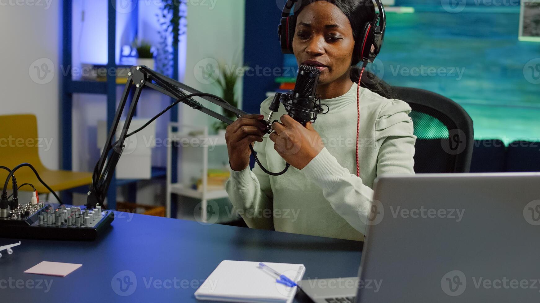 African woman recording vlog and sharing content on streaming platform using social network, checking sound at mixer. Influcencer in digital marketing doing brodcast speaking during livestreaming photo