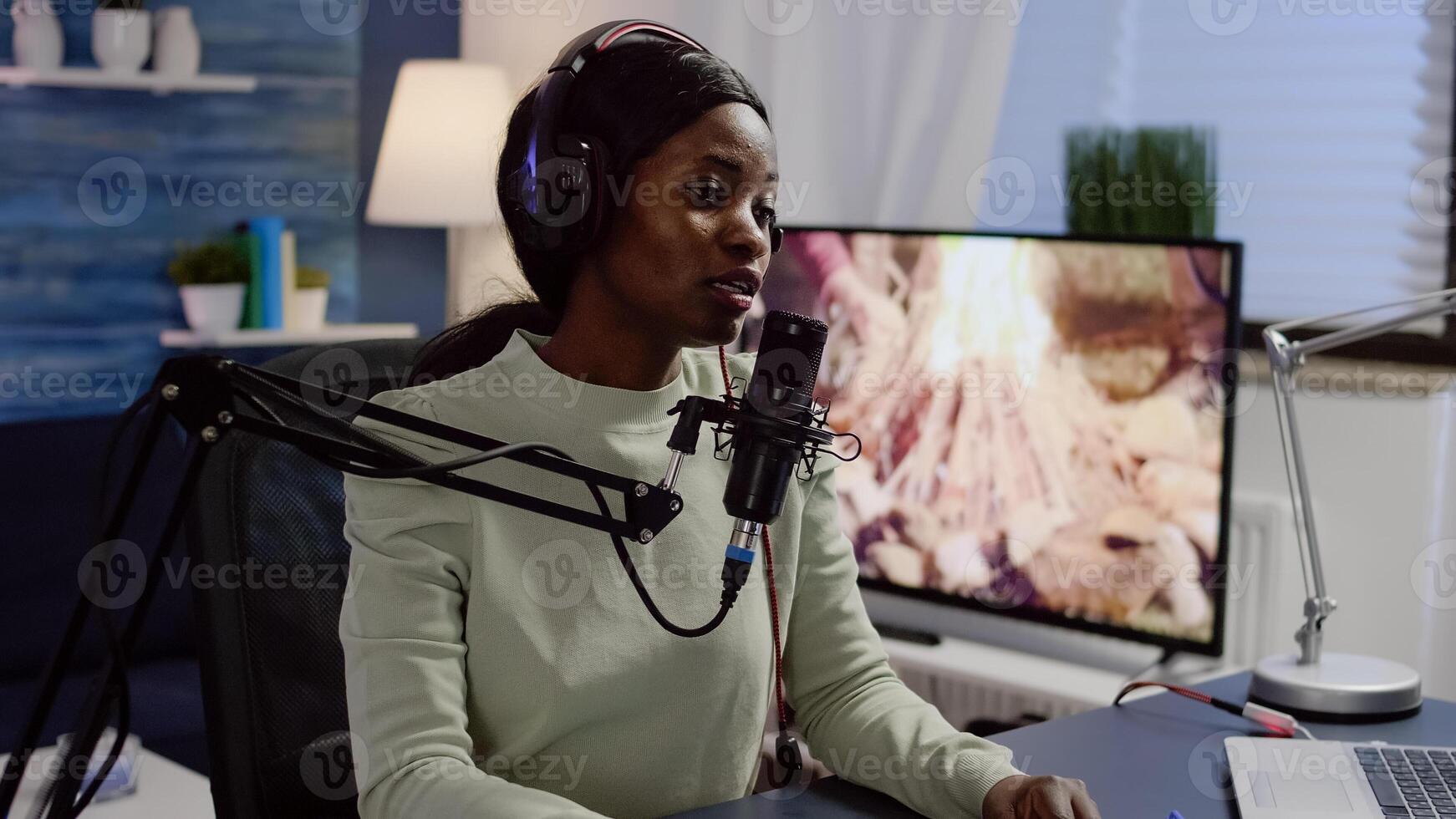 Black vlogger speaking with followers on live podcast using microphone wearing headphones. Creative online show On-air production internet broadcast host streaming live content photo