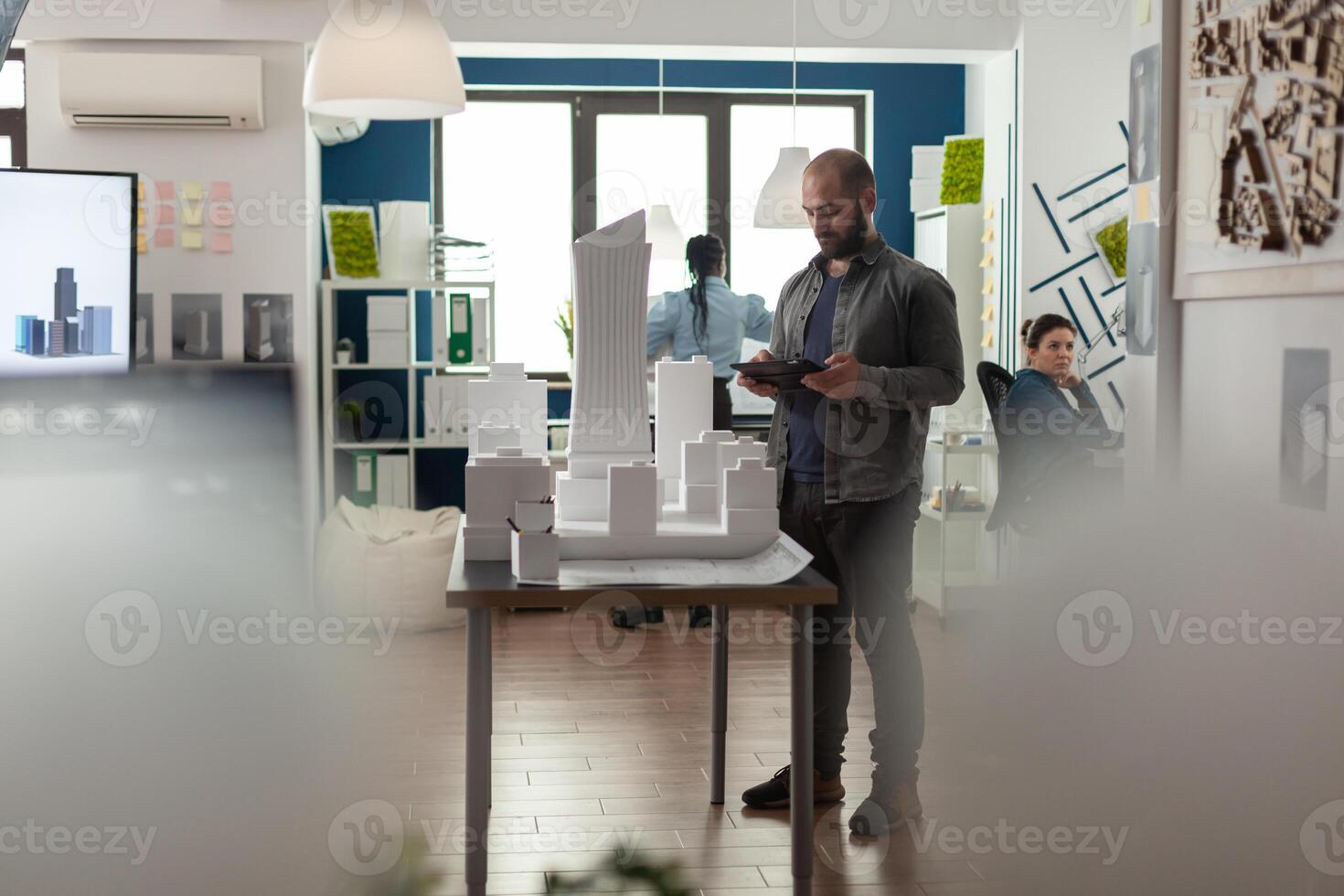 Architecture businessman working on tablet at office for designing building model maquette. Young builder inspecting development project sketch for modern structure technology photo