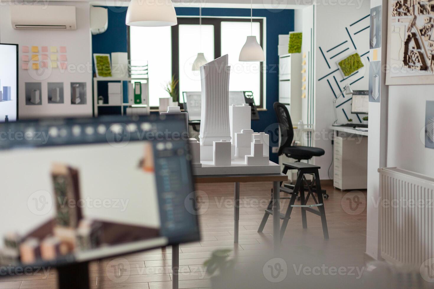 Table with scale foam model of skyscraper in empty architectural office used for urban development and architecture design. Workstation with 3D render blueprints of real estate buildings. photo