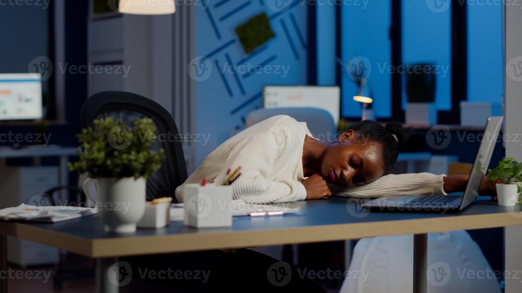Exhausted overload african business woman falling asleep on desk with open laptop monitor while working in start up company. Overworked employee using doing overtime respecting deadline, sleeping photo