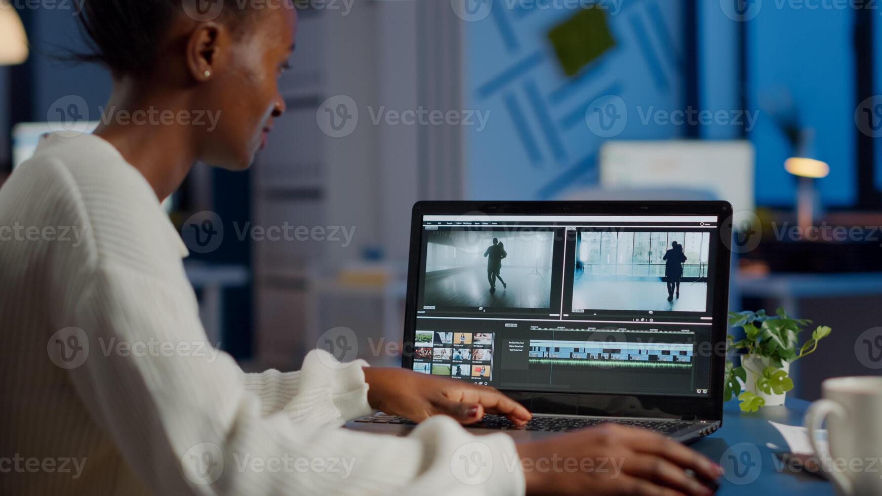 African videographer working at laptop from business office, editing and audio footage at night. Content creator using professional device modern technology network wireless processing film montage. photo