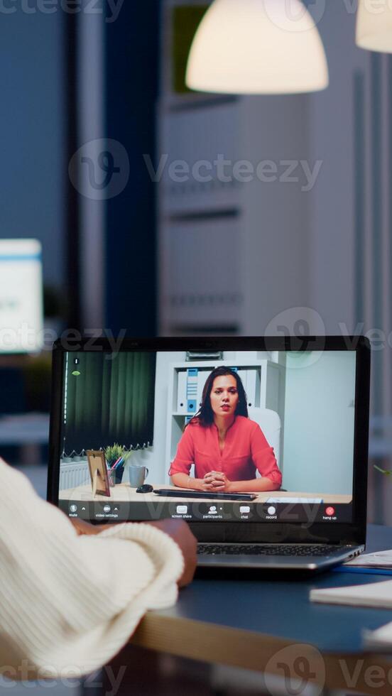 Dark skin manager woman talking with coworker during conference at midnight from business office planning financial strategy. Worker using wireless headphones discussing at virtual meeting photo