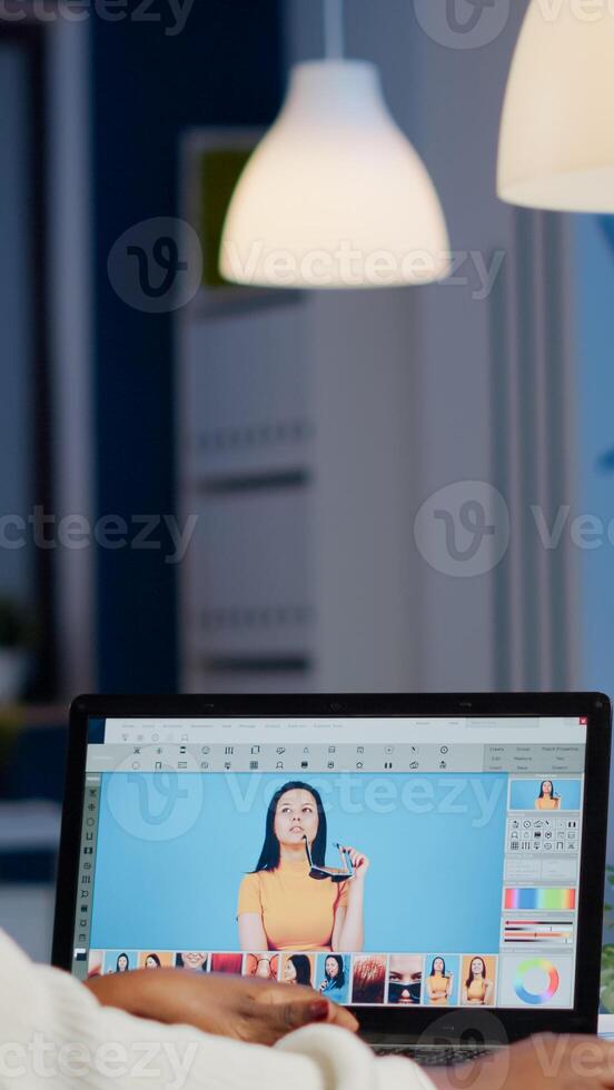 African professional woman photo retoucher working on laptop at new project in business office at night time. Content creator doing portrait retouching, artist, occupation, screen, graphic