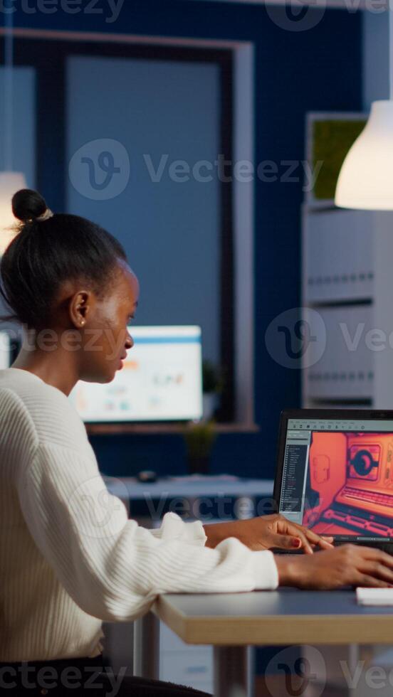 Dark skin gamer developer working at game in midnight from business office using professional laptop. African player testing online games on pc with modern technology network wireless. photo