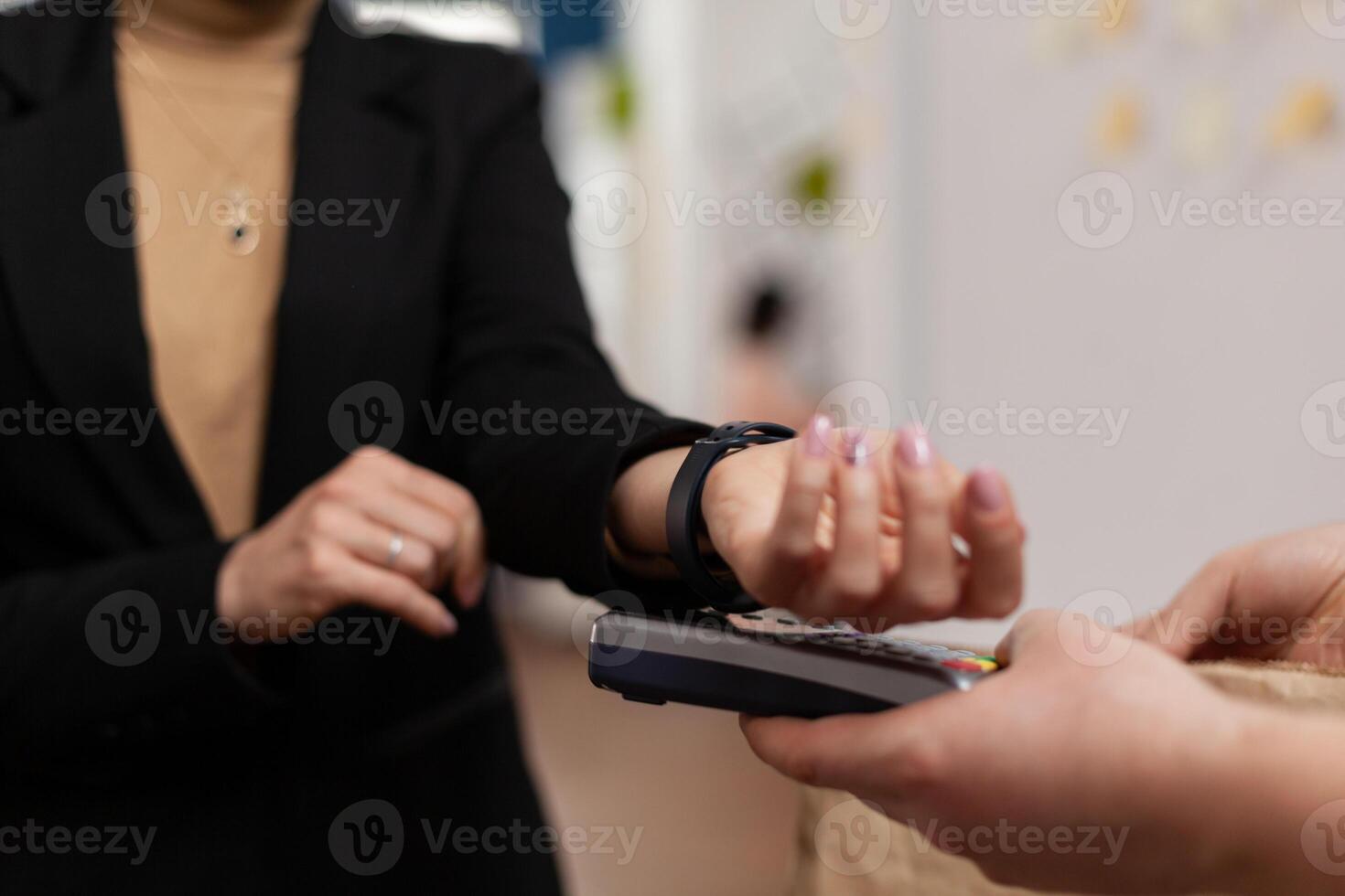 Businesswoman paying takeaway food meal order with smart watch using POS contactless terminal service during takeout lunchtime. Delivery service bringing tasty lunch deliver at workplace. photo