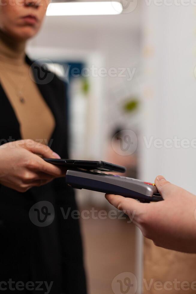Entrepreneur using smartphone for money transaction with no card, for playing delivery guy bringing fresh tasty delicious meal lunch in paper bag. Client recieving takeaway food at workplace. photo