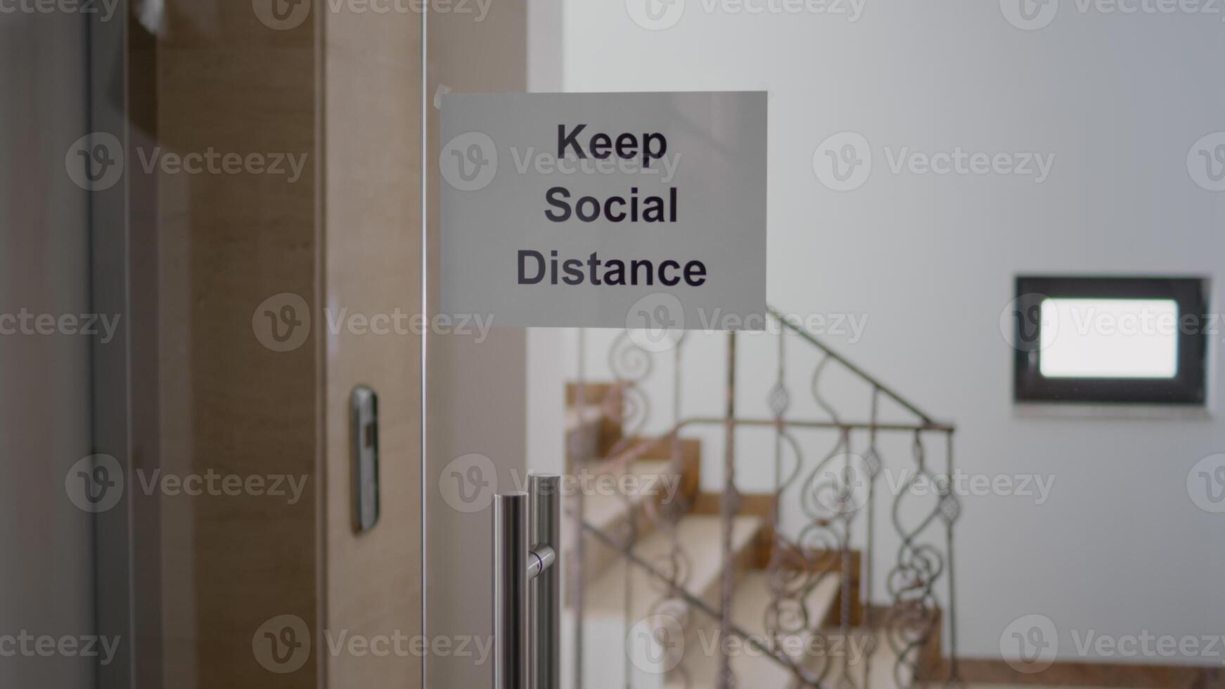 Glass office dor with keep social distance poster on it, modern office stairs duting covid 19 coronavirus pandemic, global economic crisis photo