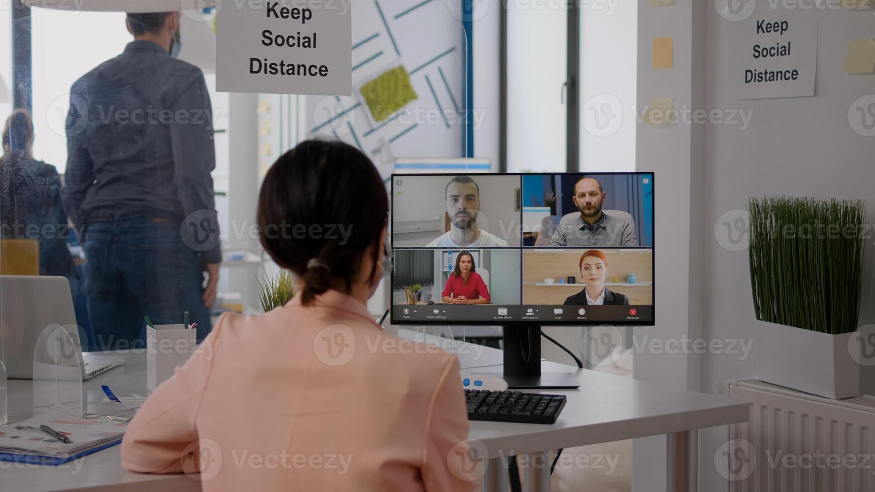 Business woman with face mask talking with team about communication project during online videocall meeting. Executive freelancer sitting at desk table in new normal office photo