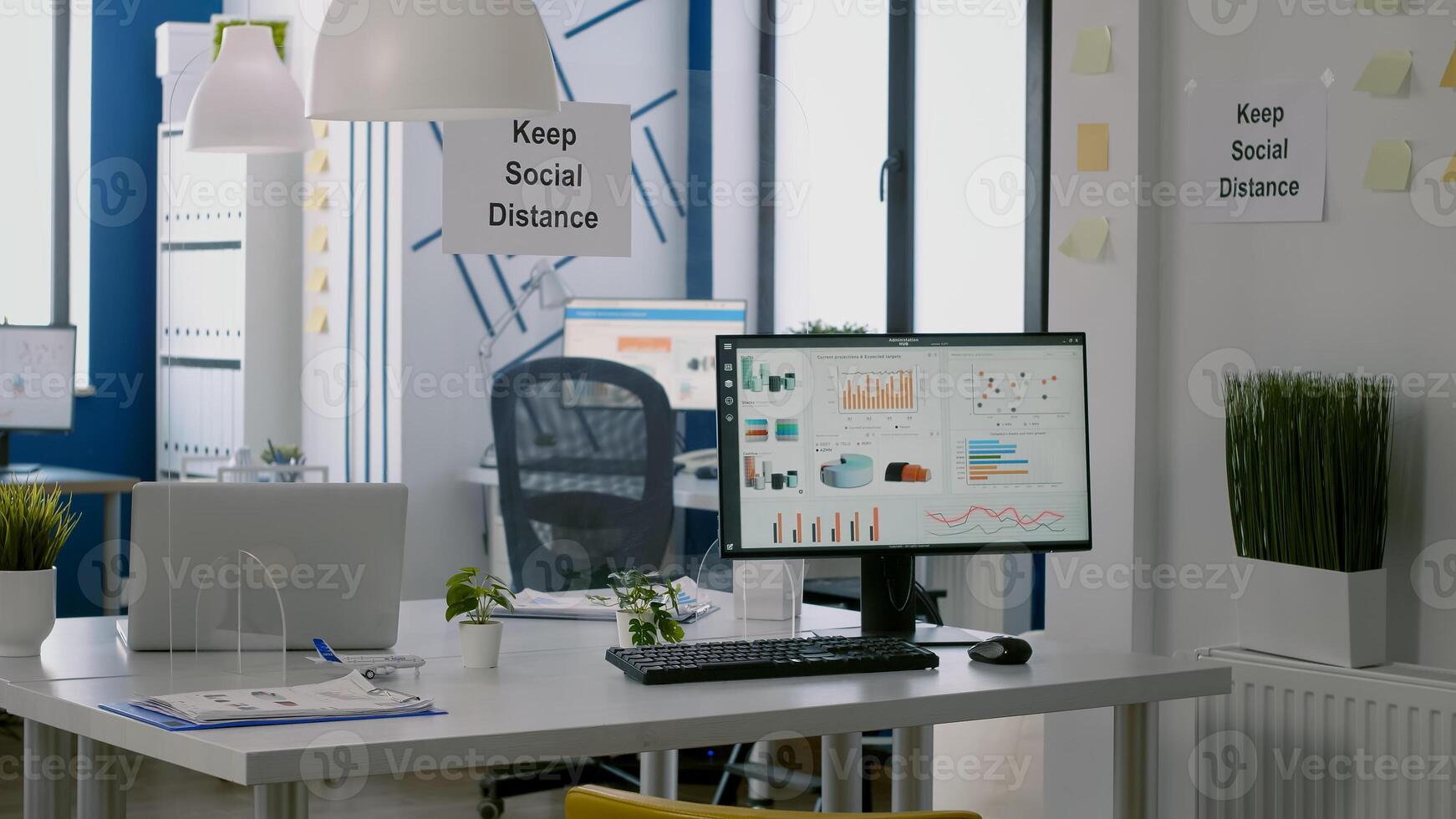 Computer with financial data in modern office interior with keep social distance sign on the walls and plastic separators. Empty corporate space with nobody in it photo