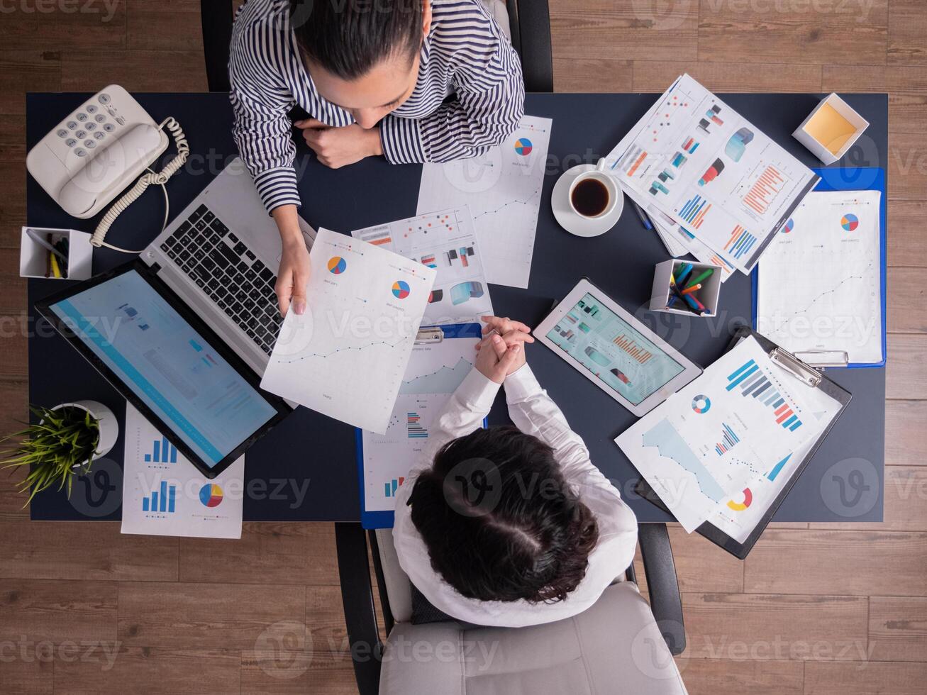 Top view of office workers meeting analyzing financial charts holding clipboard. Manager and employer discussing marketing strategy during briefing. Pointing at graphs. Business teamwork startup meeting photo