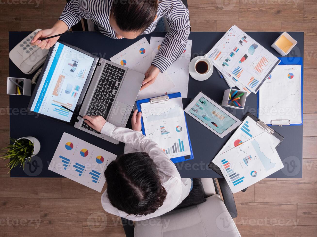 Top view of corporate business people doing good teamwork, working on financial stratey, looking at chart on paperwork, sitting at desk. Marketing team using tablet pc and laptop with documents. photo
