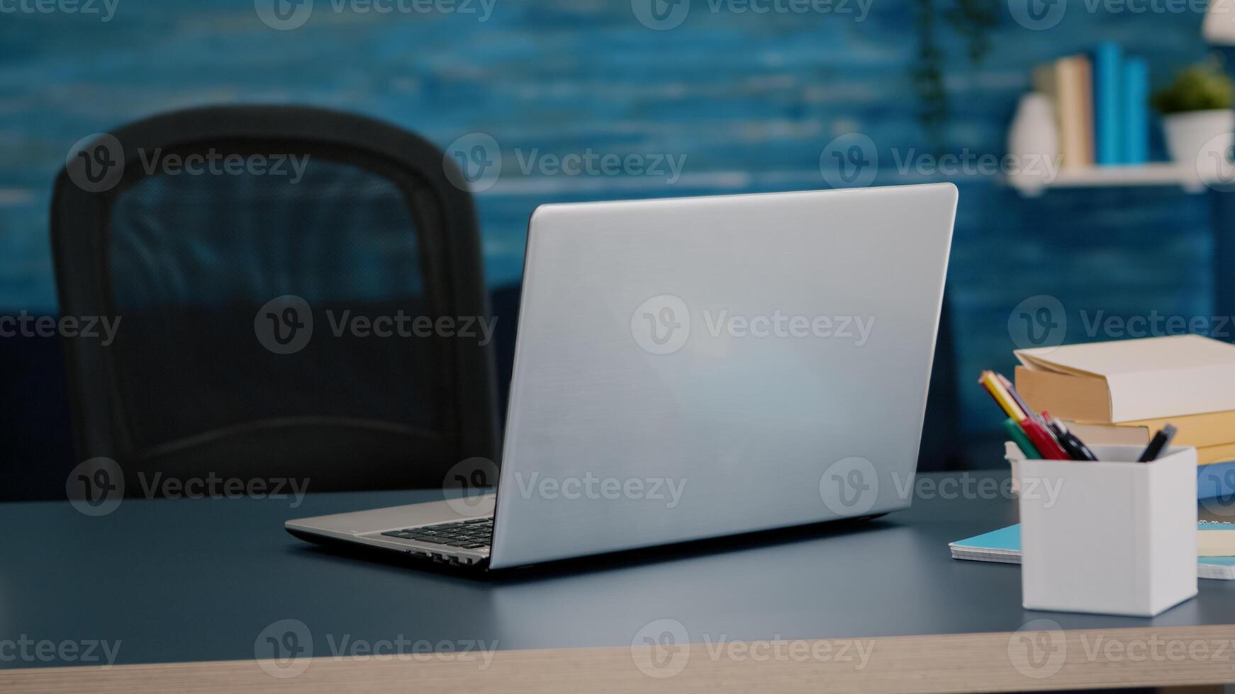 Close up of laptop computer placed on modern working desk in empty home office with blue furniture and walls. Workplace with nobody in it, place of work, workspace concept, pretty simple decor photo