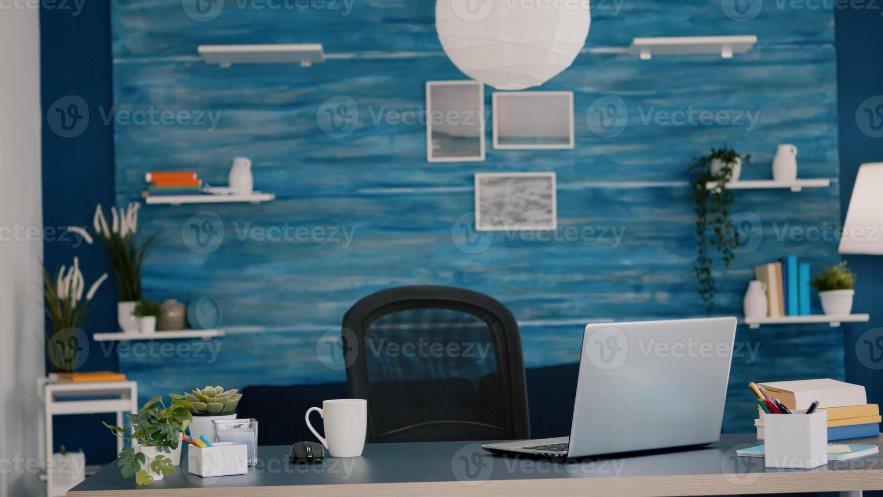 Empty home office with computer in a beautiful, spacious living room interior with blue furniture and walls. Workplace with nobody in it, place of work, workspace concept, pretty simple modern decor photo