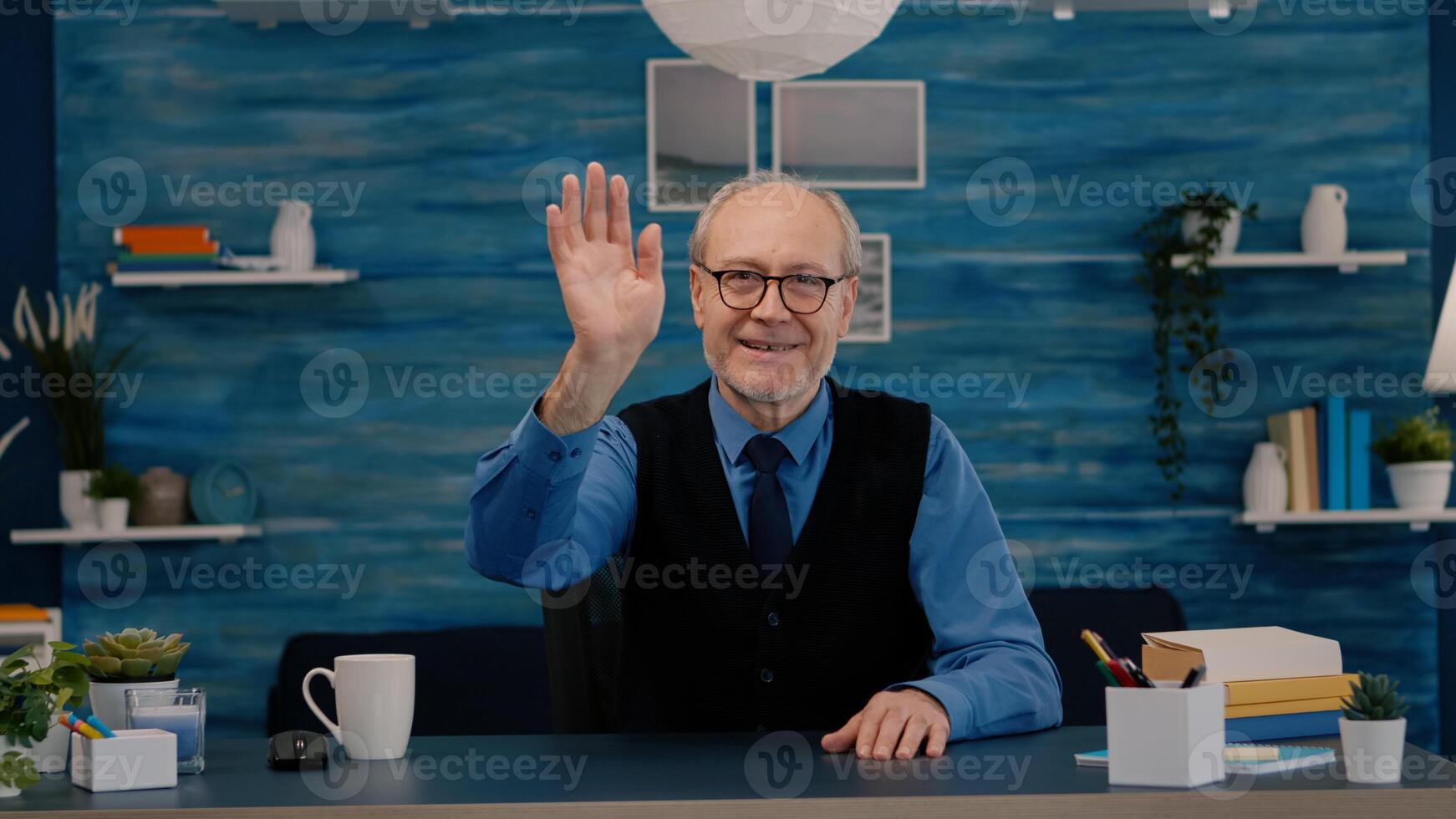 POV of elderly aged man waving during a conference with business partners working from home. Senior person using internet online chat technology webcam making virtual meeting call connection photo