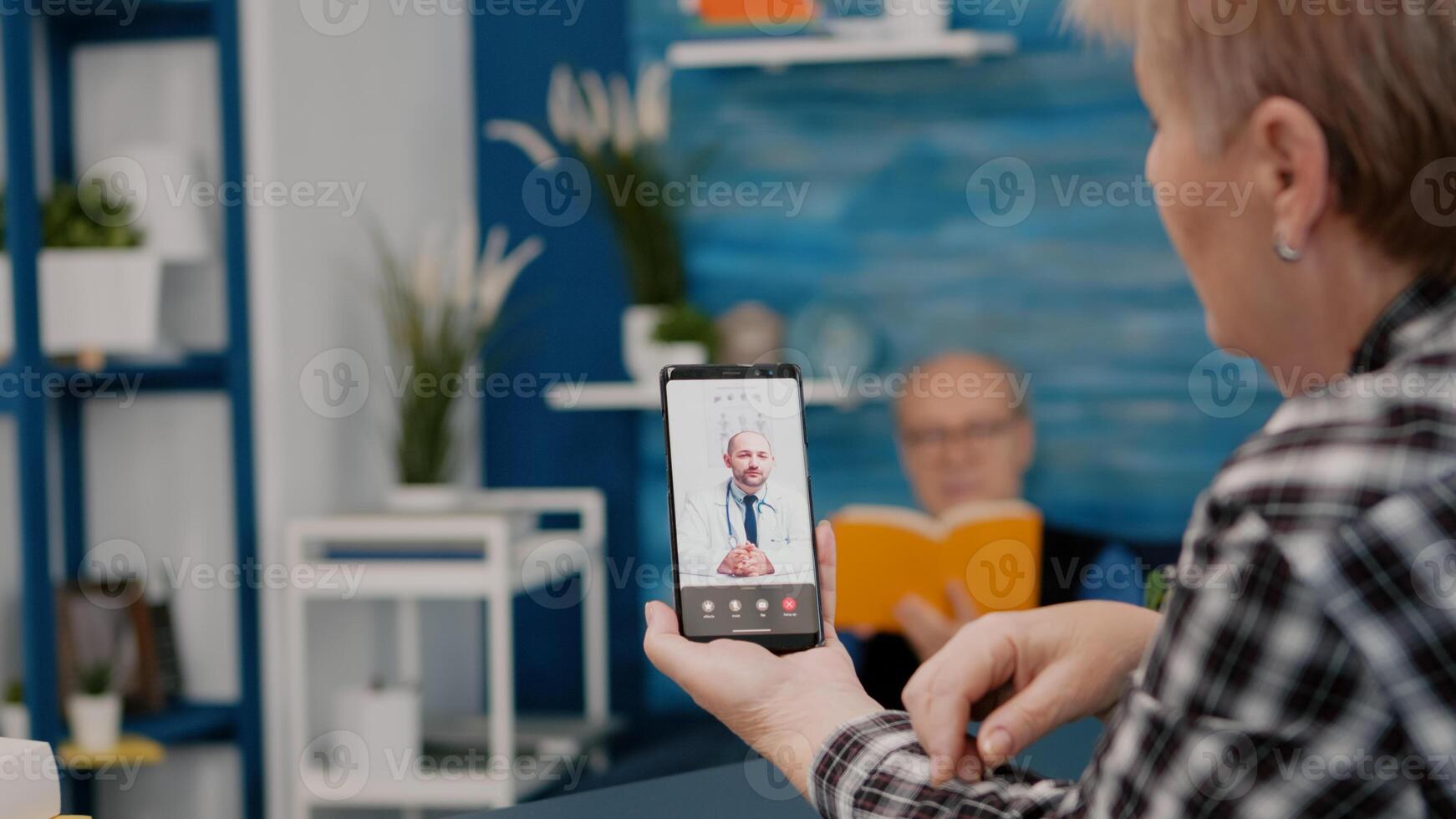 Middle aged woman talking at conference calling with remote doctor using smartphone. Remote physician using webcam prescribing medicine to sick aged patient sitting in living room via internet. photo