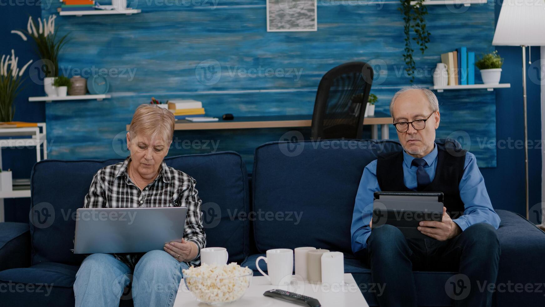 Senior couple in living room using modern gadget and technology to connect with internet. Modern old person browsing informations, surfing the web and connecting with the world photo