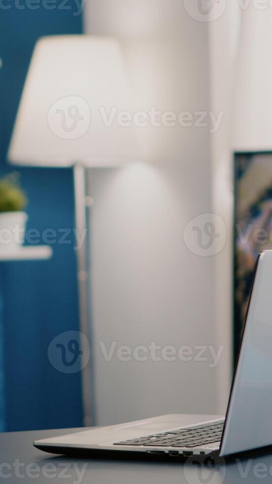 Empty workplace home office with modern design and laptop placed on desk. Living room with nobody in it, place of work, workspace concept, pretty simple modern decor of cozy apartment with television photo