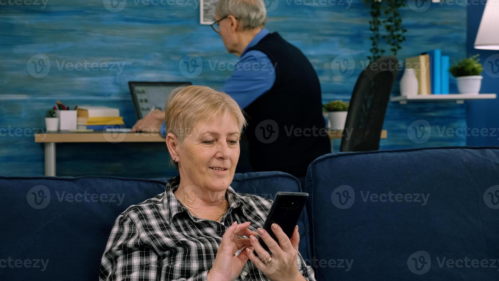 Pleasant senior older lady resting on couch, using applications on smartphone. Happy old mature woman chatting in messenger or social network with friends or children, shopping in internet store. photo