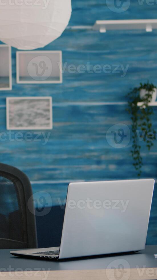 Empty home office with computer in a beautiful, spacious living room interior with blue furniture and walls. Workplace with nobody in it, place of work, workspace concept, pretty simple modern decor photo