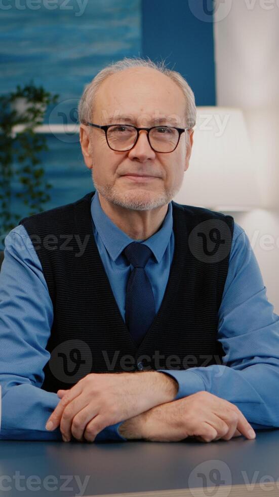 Portrait of senior man chatting and listening remote teamwork during call working from home. An elderly person using internet online chat technology webcam making virtual meeting call connection photo