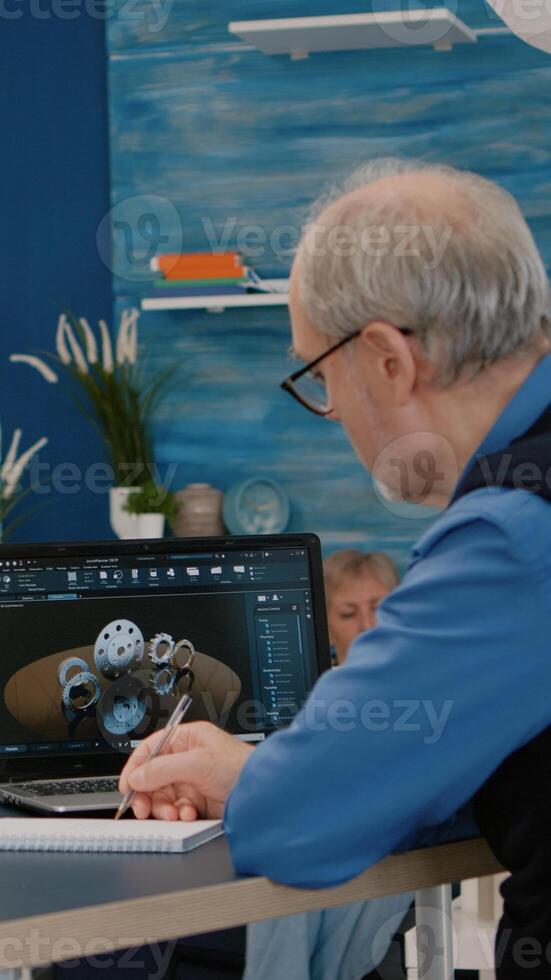 Senior remote man architect working on modern cad program analysing gears design. Industrial old engineer studying prototype idea on laptop computer showing cad software on device display photo