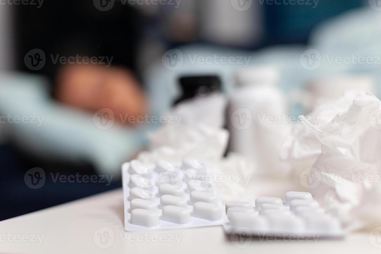 Close up of pills and napkins for ill sick woman resting on the sofa at home. Taking medicine for cold and flu, fever, seasonal virus symptoms. Bottles with drugs for recovery treatment photo