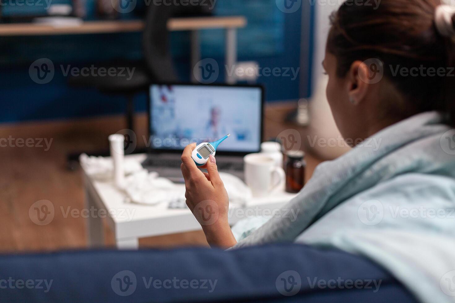 Sick woman on online conference with doctor at home for diagnostic and assistance. Caucasian young patient on webcam telemedicine consultation to treat flu virus fever temperature photo
