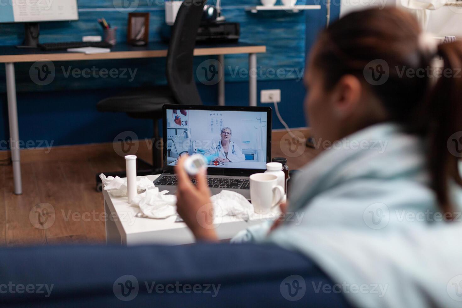 Caucasian woman on webcam communication with doctor for medications support against flu cold virus fever. Young patient at home using telemedicine for healthcare, holding a thermometer photo