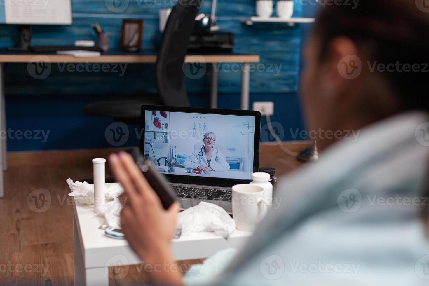 Cold young woman calling doctor from computer to treat flu illness virus fever temperature. Patient with thermometer on online consultation for treatment pills diagnostic assistance photo