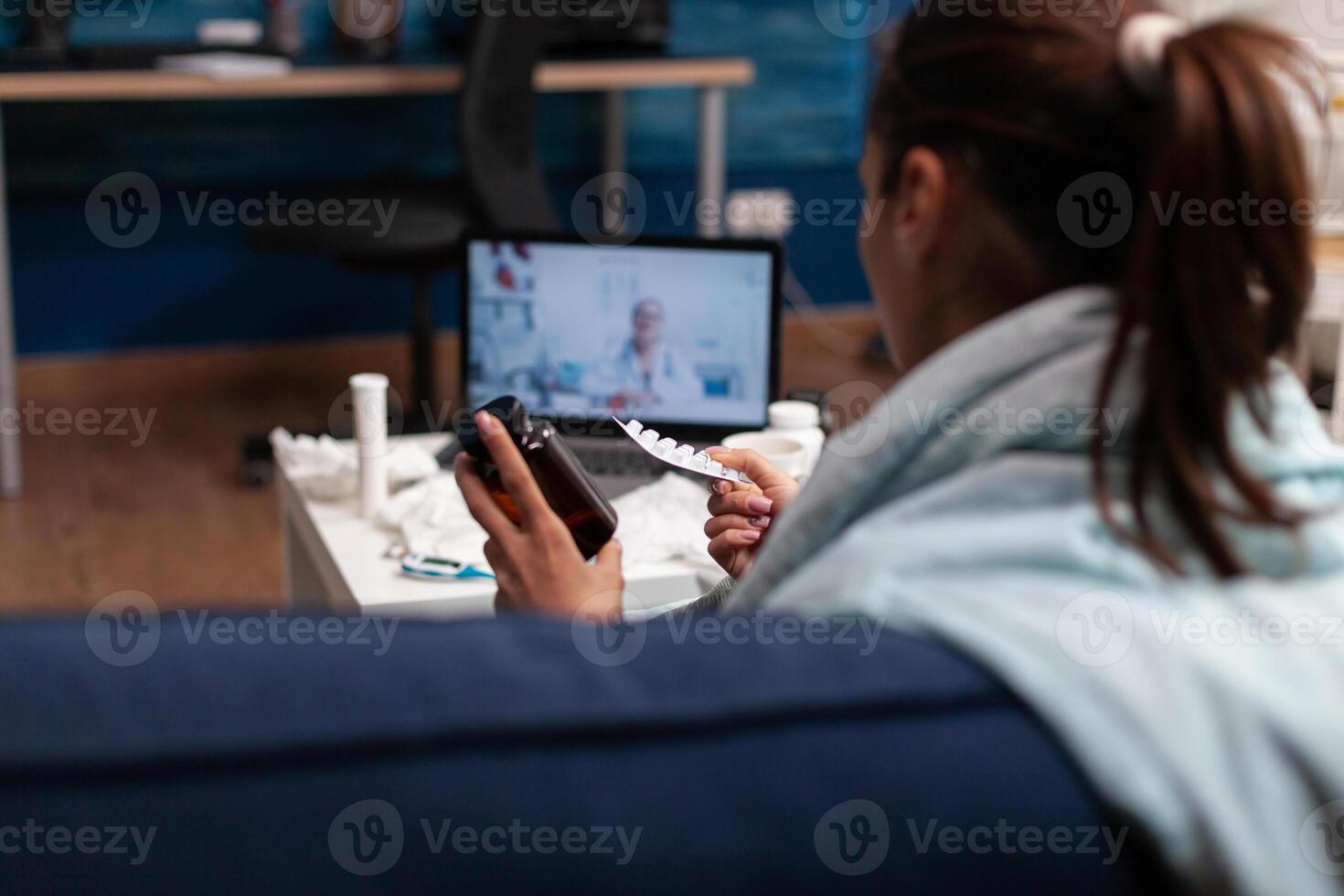 Unwell woman at home on webcam doctor consultation online for assistance support medications. Young caucasian patient with fever temperature cold illness on telemedicine against virus photo