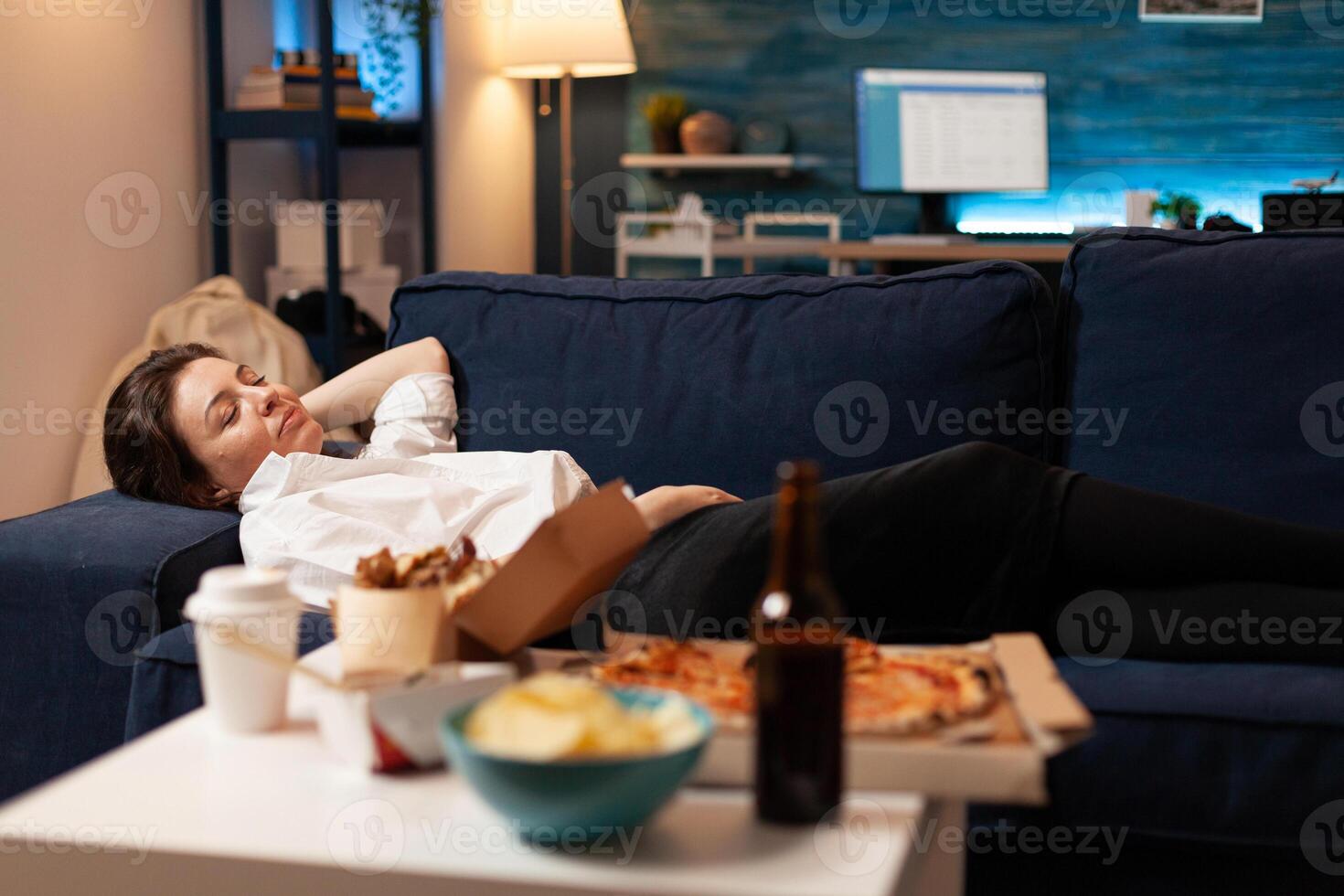 Caucasian female falling asleep after eating junk-food in living room late at night during takeaway food home delivered. Tasty delicious meal lunch order. Unhealthy snack fastfood photo