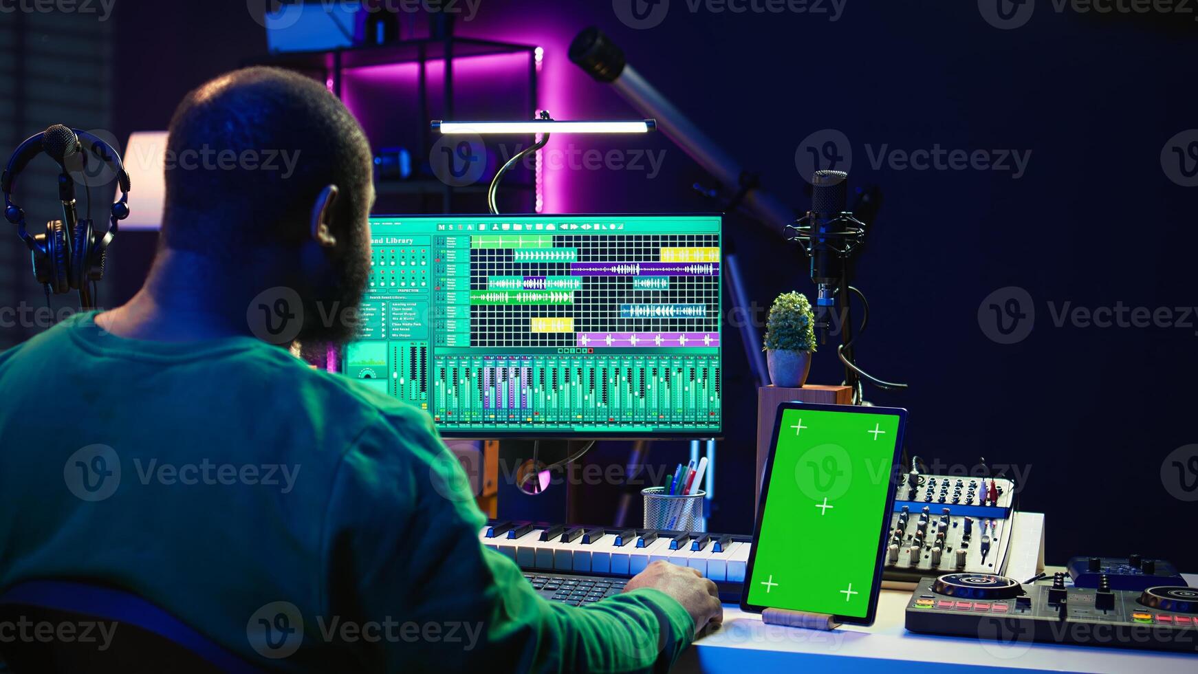 Songwriter composer mixing and mastering tracks next to green screen, operating on digital audio pc interface to add sound effects on new recordings. Technician in home studio. Camera B. photo