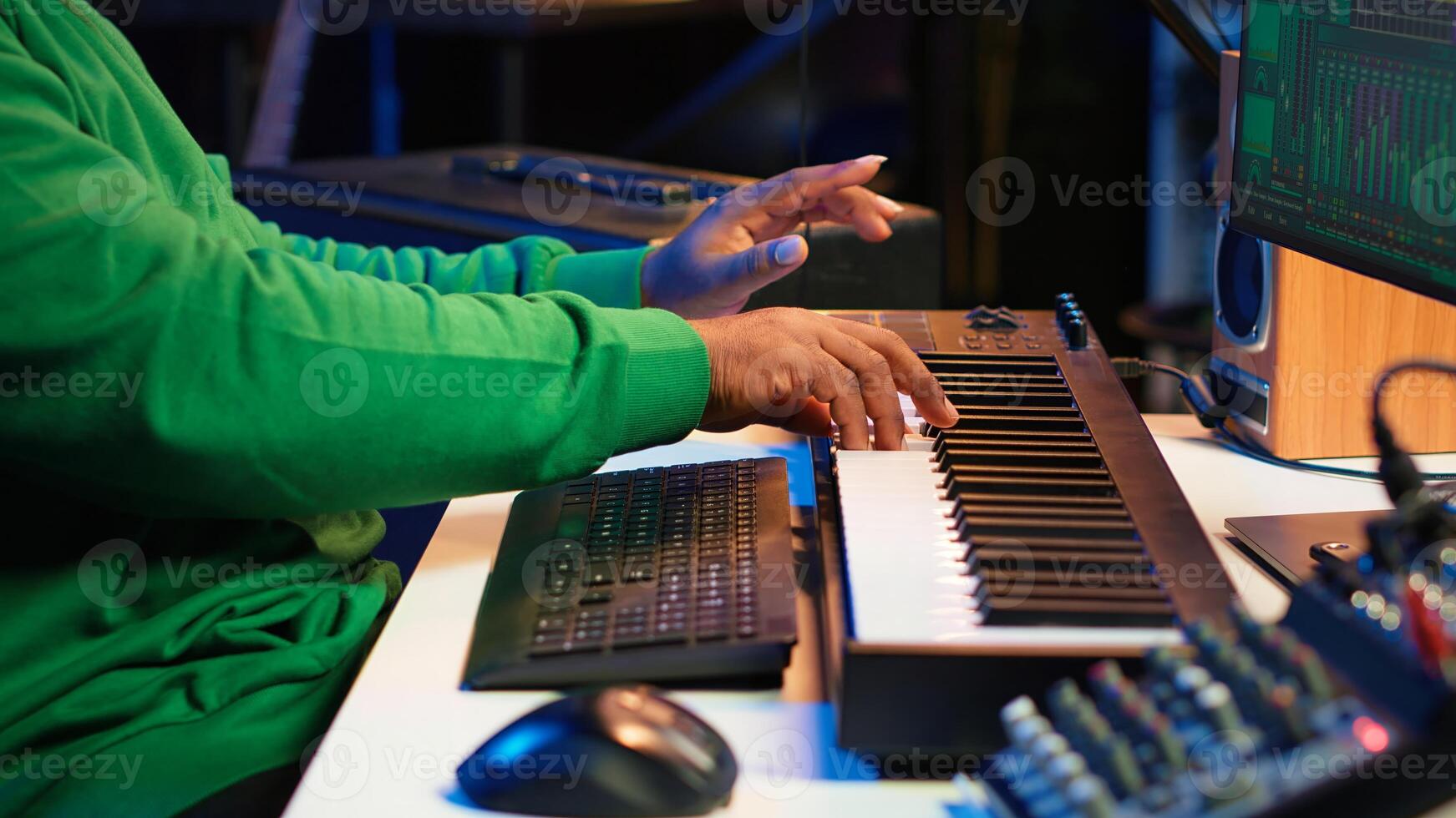 African american audio technician using piano synthesizer keys to add sound effects in post production, editing tunes with digital software and mixing console. Male artist in home studio. Camera A. photo
