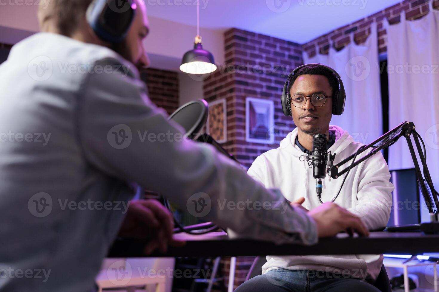 Podcast presenter having live discussion with man, streaming it for audience on internet entertainment show. Influencer enjoying chat with guest, broadcasting in personal home studio photo