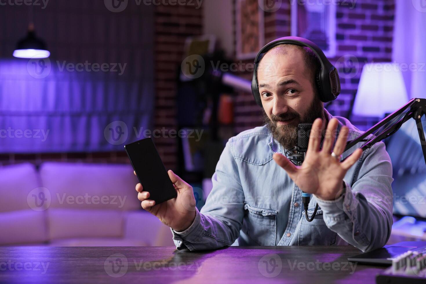Portrait of tech vlogger listing top 5 best smartphones on the market in rgb lights home studio. Entertaining content creator filming technology listicle for interested audience photo