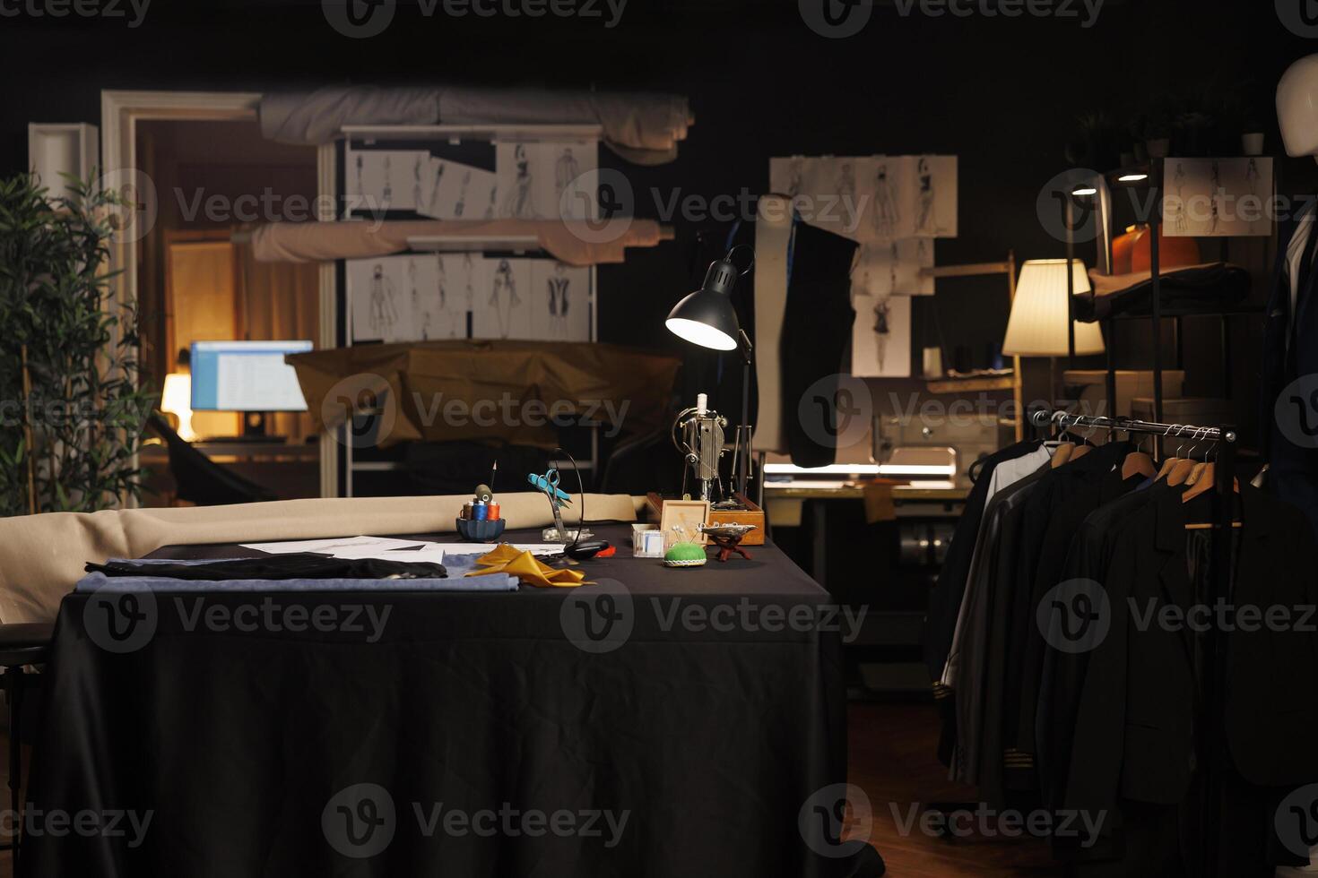 Table full of professional tailoring instruments used for manufacturing bespoke sartorial attire. Sewing machine, pins, needles, thread spools on table in atelier studio workspace photo