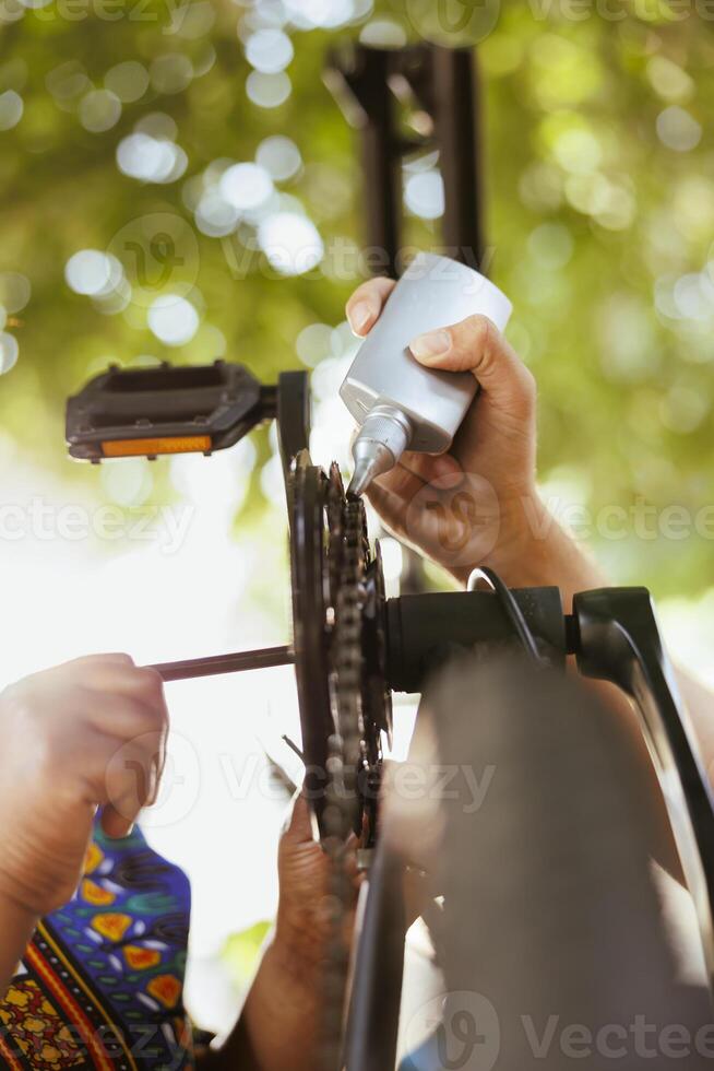 Close-up of diverse hands utilizing professional tools to repair and grease bike components. Detailed shot of healthy hands diligently fixing modern bicycle for seamless and secure outdoor cycling activity. photo