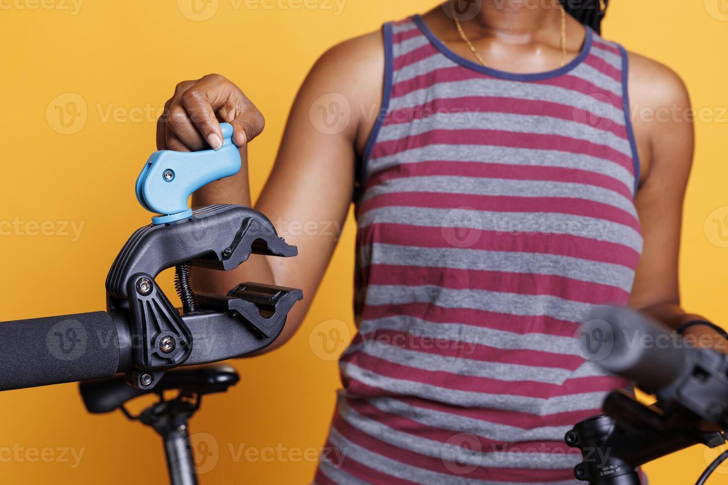 Female cyclist examines and adjusts repair stand in close-up to ensure safety to hold bicycle during maintenance. View in detail of black woman getting ready to fasten the bike frame for mending. photo