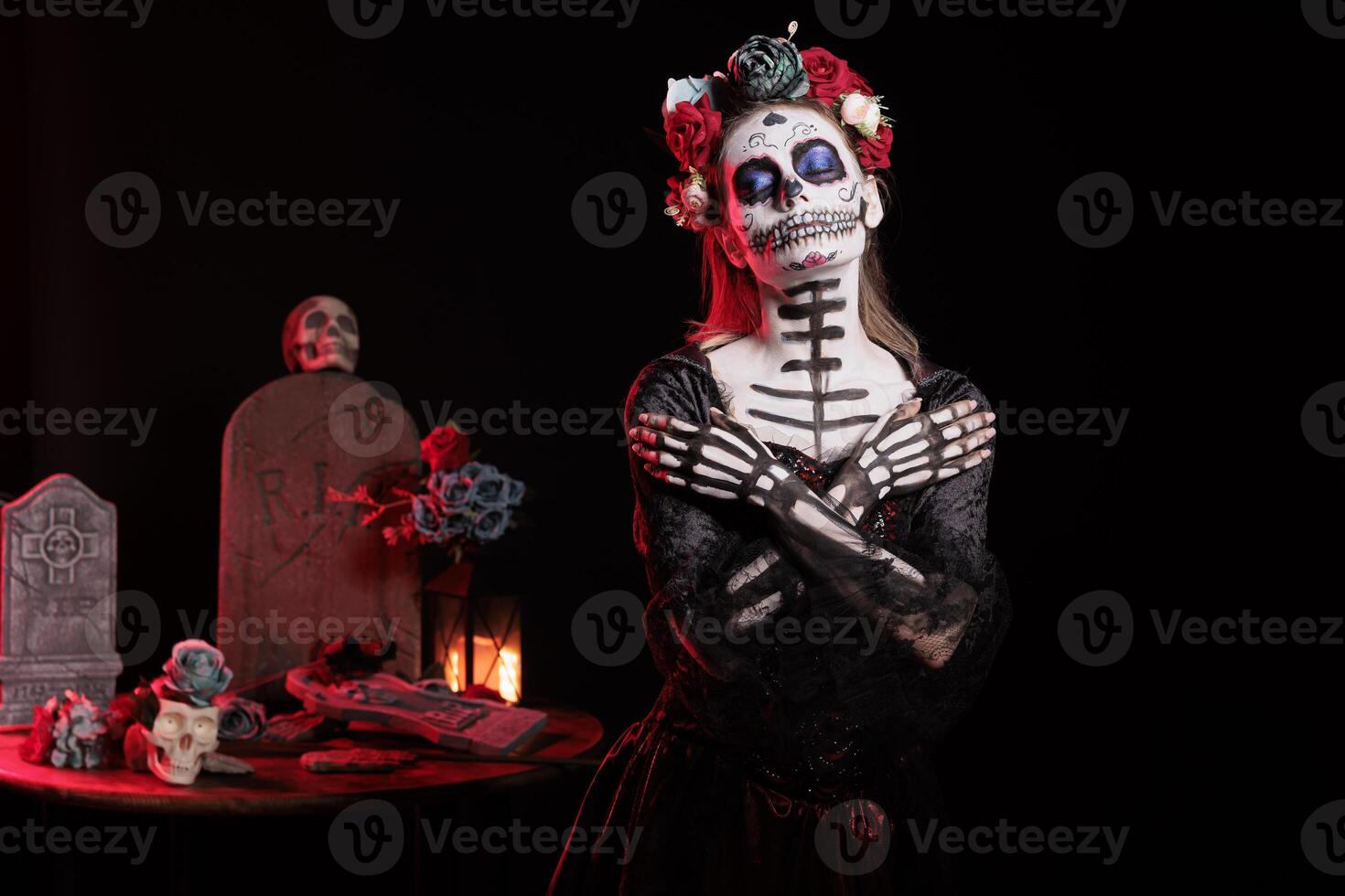 Woman with arms crossed on chest at Day of the Dead event to remember the deceased, celebrating their memory. Lady pretends to be dead at mexican holiday of remembrance for those who have passed photo